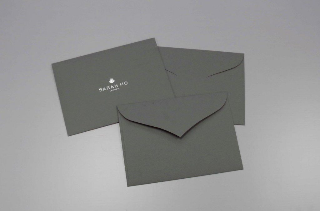 Bespoke tuck-flap curved diamond flap envelopes with silver foil print flat sheet conversion from GF Smith Dark Grey Colorplan Linen Embossed